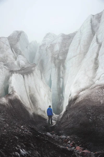 Δωρεάν με ένα τσεκούρι πάγο ορειβάτης στέκεται στους πρόποδες του παγετώνα μεγάλη δίπλα σε μια επική ρωγμή στην ομίχλη στα βουνά. Ανυπέρβλητο εμπόδιο — Φωτογραφία Αρχείου