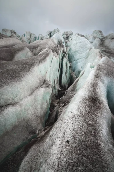 Close-up Crack es una grieta azul profunda que se encuentra en la capa de hielo y barro negro en el glaciar. Amplio ángulo y cielo dramático —  Fotos de Stock