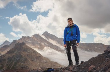 Bir şapka ve güneş gözlüğü bir dağcı gökyüzü arka plan ve Kafkasya karla kaplı dağlar karşı elinde bir buz balta ile profesyonel bir rehber portresi