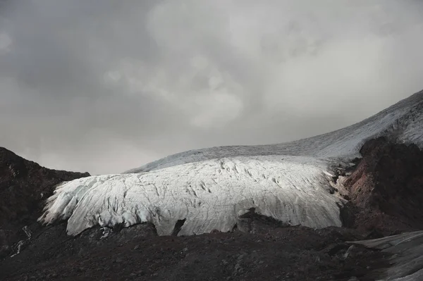 Paesaggio montano polveroso pendio vulcanico sporco con ghiacciaio fuso incrinato. Riscaldamento globale. Ghiacciai del Caucaso settentrionale — Foto Stock