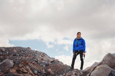 Bir şapka ve güneş gözlüğü bir dağcı gökyüzü arka plan ve Kafkasya karla kaplı dağlar karşı elinde bir buz balta ile profesyonel bir rehber portresi