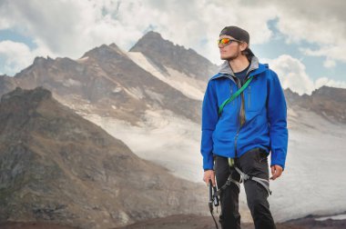 Bir şapka ve güneş gözlüğü bir dağcı gökyüzü arka plan ve Kafkasya karla kaplı dağlar karşı elinde bir buz balta ile profesyonel bir rehber portresi