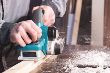 Bir marangoz ahşap elektrikli el aletleri Çalışma elleri. Elektrikli planya çalışmalarını yakın çekim