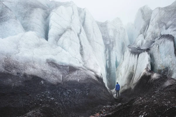 Un arrampicatore con una piccozza si trova ai piedi del Grande Ghiacciaio accanto a un'epica crepa nella nebbia delle montagne. ostacolo insormontabile — Foto Stock