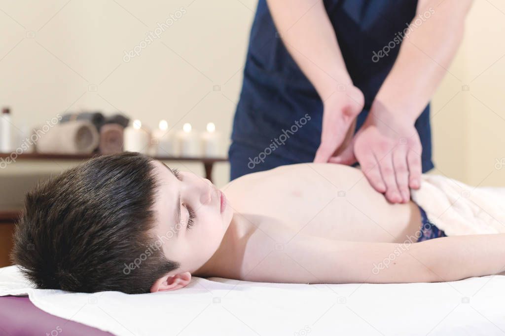 A little boy at the reception at a professional masseuse. Male manual worker gives massage to the front of the child