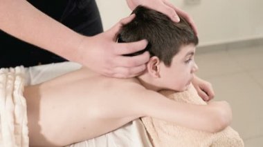 Bir erkek fizyoterapist masör masaj bir masaj yatakta yatarken küçük boy gülümseyerek için rahatlatıcı bir şifa yapar. Baş masajı