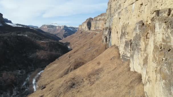 Vista aérea del movimiento a lo largo de la pared rocosa del cañón en la garganta en el Cáucaso. Muy cerca de la roca en invierno cuando hay poca nieve. 4k — Vídeos de Stock