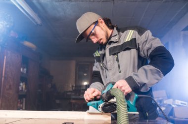 Elektrik düzlemin bir ev ahşap atölyesinde çalışan genç bir marangoz portresi. Kavramı bir iş fikri ve bir ağaç işleme başlangıç