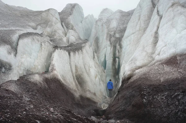 Un arrampicatore libero con una piccozza si trova ai piedi del Grande Ghiacciaio accanto a epiche crepe nella nebbia in montagna. ostacolo insormontabile — Foto Stock