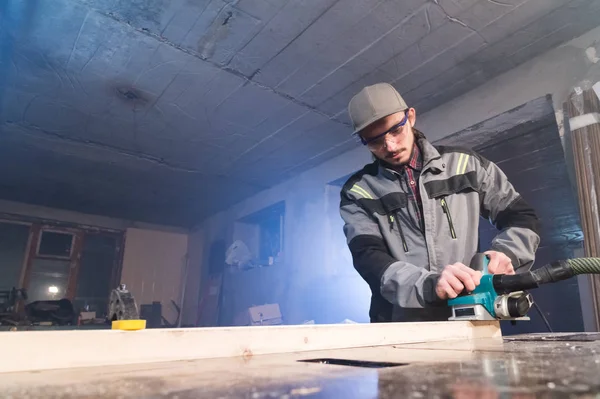 Elektrik düzlemin bir ev ahşap atölyesinde çalışan genç bir marangoz portresi. Bir iş fikri ve bir ağaç işleme başlangıç kavramı. Geniş açı