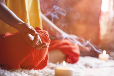 Parmak mudra aroma tütsü yanında yapım lotus pozisyonunda yakın çekim pencereden evde mum çevrili bir kız meditasyon