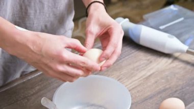 Eller close-up. Kız ev mutfak sonları, masanın üzerinde yatan bir blender arka planı plastik bir kaseye yumurta tavuk