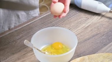 Eller close-up. Kız ev mutfak sonları, masanın üzerinde yatan bir blender arka planı plastik bir kaseye yumurta tavuk