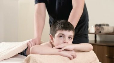 Bir erkek fizyoterapist masör masaj bir masaj yatakta yatarken küçük bir çocuk için rahatlatıcı bir şifa yapar. El ve omuz masajı