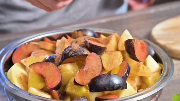 Close-up of a female hand in a home kitchen squeezes part of a lemon in a metal plate with sliced plum fruit apples and pears. Healthy and healthy food — Stock Video