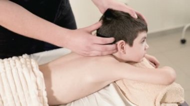Bir erkek fizyoterapist masör masaj bir masaj yatakta yatarken küçük boy gülümseyerek için rahatlatıcı bir şifa yapar. Baş masajı