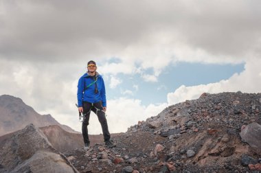 Bir şapka ve güneş gözlüğü bir dağcı gökyüzü arka plan ve Kafkasya karla kaplı dağlar karşı elinde bir buz balta ile gülen profesyonel kılavuzunun portresi