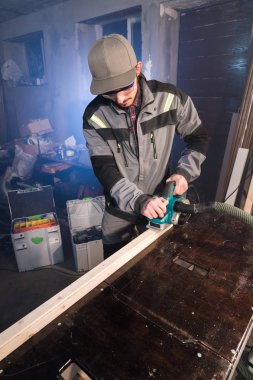 Elektrik düzlemin bir ev ahşap atölyesinde çalışan genç bir marangoz portresi. Bir iş fikri ve bir ağaç işleme başlangıç kavramı. Geniş açı