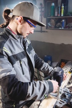 Bir işçi bir ev atölye elinde elektrikli freze kesici ile genç marangoz joiner portresi. Bir iş kurma. Usta