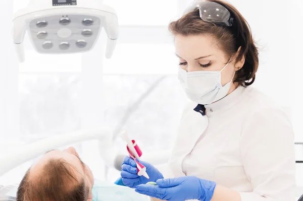 Γυναίκα γιατρός κάνει ένα απόρριμμα των δοντιών. Αναμιγνύει αντιδραστήρια για σύνθεση — Φωτογραφία Αρχείου