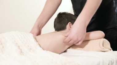 Bir erkek fizyoterapist masör masaj bir masaj yatakta yatarken küçük boy gülümseyerek için rahatlatıcı bir şifa yapar. Bel ve sırt Masaj