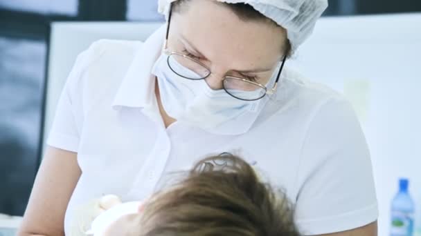 Kobieta lekarz dentysta w okulary maski i white cap bada jamy ustnej pacjenta. Dentyści pracy — Wideo stockowe