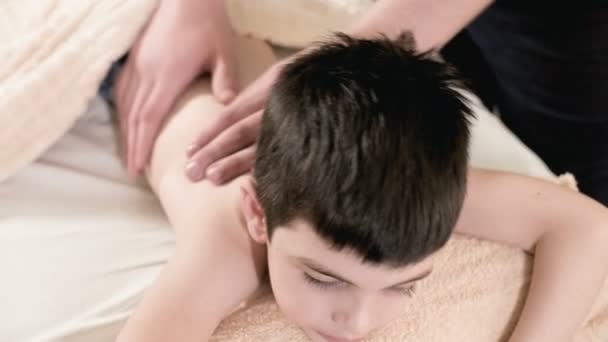 Szczelnie-do góry mężczyzna fizjoterapeuta masażysta sprawia, że uzdrowienie masaż do małego chłopca leżącego na łóżku masaż relaksacyjny. Masaż pleców — Wideo stockowe