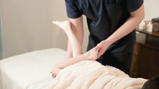 En manlig sjukgymnast massör gör en helande avslappnande massage och stretching en liten pojke som liggande på en massage säng. Stretching senor och muskler — Stockvideo