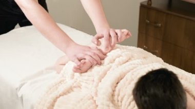 Bir erkek fizyoterapist masör bir rahatlatıcı masaj ve küçük bir çocuk bir masaj yatakta yatarken germe şifa yapar. Tendon ve kas germe