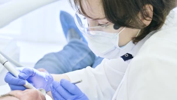 Close-up de uma mulher dentista examinando a cavidade oral de um paciente do sexo masculino na idade. Alto trabalho profissional chave de um dentista na clínica odontológica — Vídeo de Stock