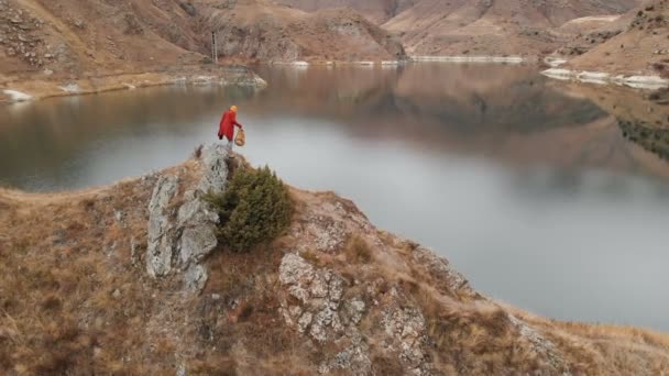 Vista aérea de una niña se sienta en una roca en la orilla de un lago. Viajes vídeos — Vídeo de stock
