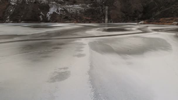 Vista aérea de un vuelo bajo sobre un lago congelado en invierno rodeado por las montañas del Cáucaso después del atardecer a la hora azul — Vídeo de stock