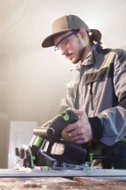 Bir işçi bir ev atölye elinde el ile dairesel güç ile genç marangoz joiner portresi gördüm. Bir iş kurma. Usta