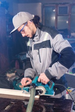 Elektrik düzlemin bir ev ahşap atölyesinde çalışan genç bir marangoz portresi. Kavramı bir iş fikri ve bir ağaç işleme başlangıç