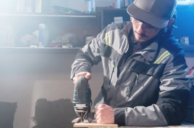 Bir işçi bir ev atölye elinde elektrikli testere ile bir genç marangoz joiner portresi. Bir iş kurma. Usta