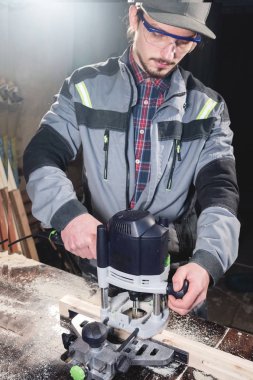 Bir işçi bir ev atölye elinde elektrikli freze kesici ile genç marangoz joiner portresi. Bir iş kurma. Usta