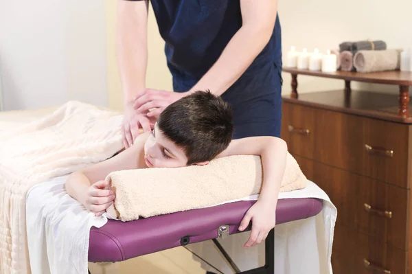 Mały chłopiec rozluźnia z masażu leczniczego. Mężczyzna masażysta sprawia, że masaż leczniczy pleców dziecka — Zdjęcie stockowe
