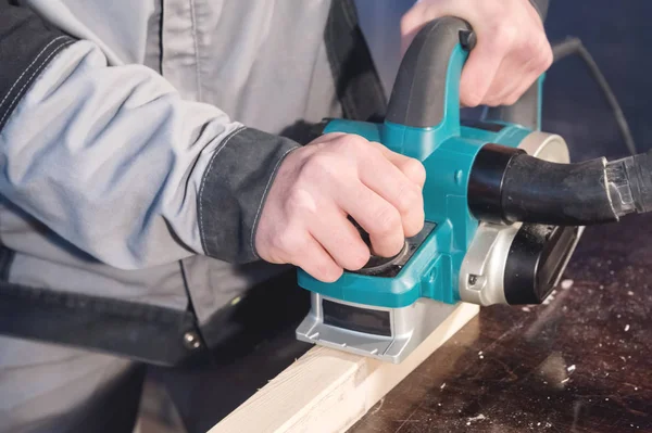 As mãos de um carpinteiro trabalhando ferramentas de madeira poder. Fechar o trabalho da plaina elétrica — Fotografia de Stock