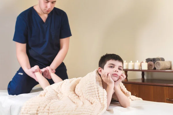 Trochę znudzony chłopiec pacjenta w recepcji o profesjonalnym masażom. Masażu stóp — Zdjęcie stockowe