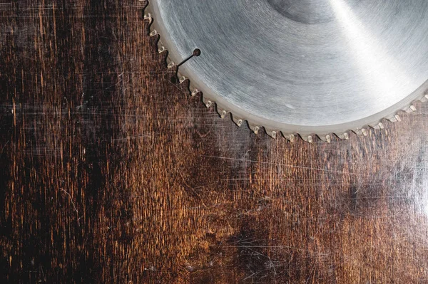 Close-up used blade circular saw on the background of the wooden table Verscak. Workshop for the production of wooden products. Joiners cutting tool