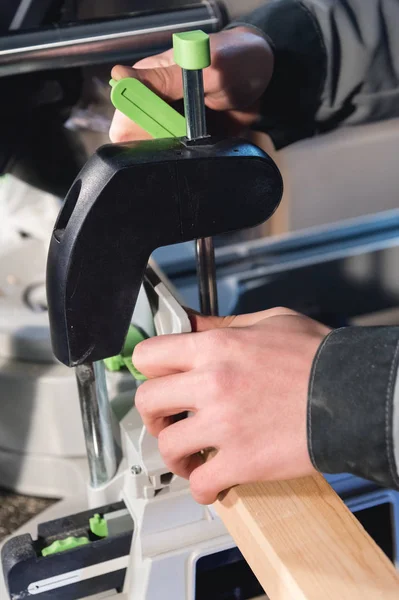 Närbild av händerna på en manlig snickare som arbetsstycket i klämmorna av en cirkulär maskin. Handarbete. Starta ett företag — Stockfoto