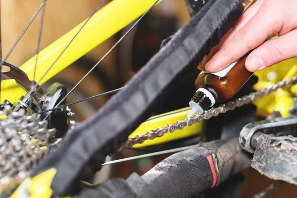 Yakın çekim, bir el, ustaları tarafından liderliğindeki mans ev atölye özel bir yağ ile bir dağ bisikleti Bisiklet zincirini yağlamak