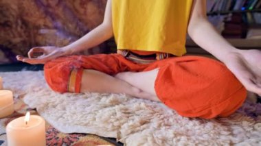 Kamera hareketi kayar. Vücuttaki el ve ayak lotus pozisyonunda bir kızın yakın çekim. Manevi büyüme. Meditasyon mum by çevrili. Sığ Dof