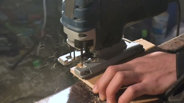 Gros plan. Un menuisier coupant une planche de bois avec un puzzle électrique. Mouvement lent des particules de poussière et lame de scie — Video