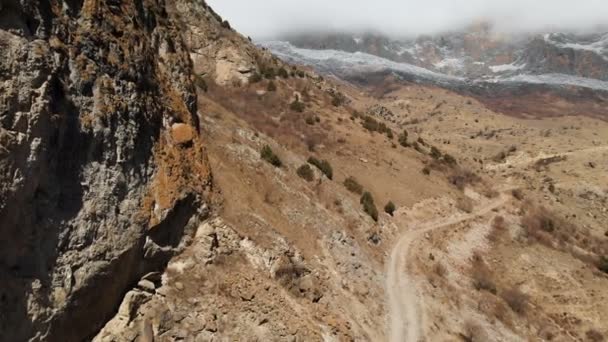 Le montagne dell'Alta Balkaria. Veduta aerea della gola con una strada sterrata e basse nuvole nelle montagne del Caucaso. giornata di sole — Video Stock