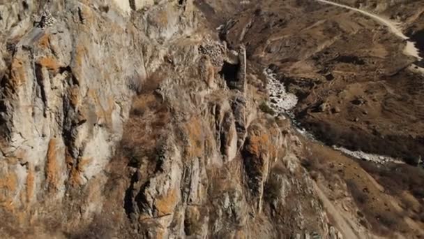 Las ruinas de antiguas torres sobre una roca en las montañas de los Balcanes Superiores. Vista aérea del desfiladero con un camino de tierra y un río de montaña en las montañas del Cáucaso. día soleado — Vídeo de stock