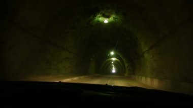 Arabanın ön camından görün. Araba, loş aydınlatma ve bir kır yolu ile bir kaya yapılmış bir tünel üzerinden sürmek. Kafkaslar dağ yolları