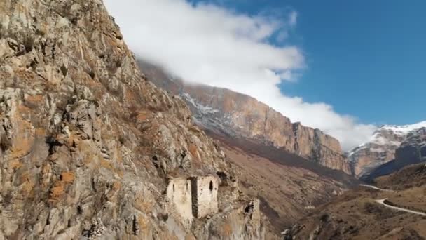 Les ruines d'anciennes tours sur un rocher dans les montagnes des Balkans supérieurs. Vue aérienne de la gorge avec un chemin de terre et une rivière de montagne dans les montagnes du Caucase. journée ensoleillée — Video