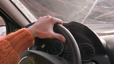 Şehir dışında bir araba sürüş turuncu bir kazak bir kadın elini yakın çekim. Yavaş hareket kadın araba kullanıyor