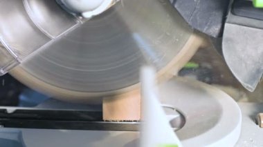 Büyük yakın çekim. Elektrikli daire testere makinesi ile ahşap tahta kesme bir marangoz. Toz parçacıklarının ve testere bıçağının yavaş hareketi